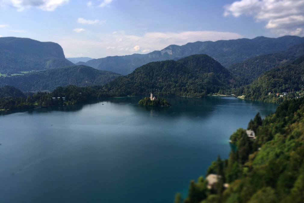 Bird's-eye view of a deep blue lake and green, forested mountains