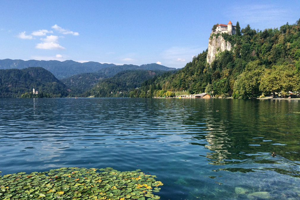 Medieval castle perched on a cliff above a clear blue lake