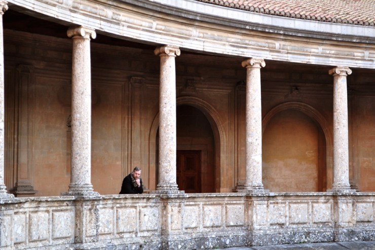 Man on the balcony of a large Florentine-style patio with Ionic columns