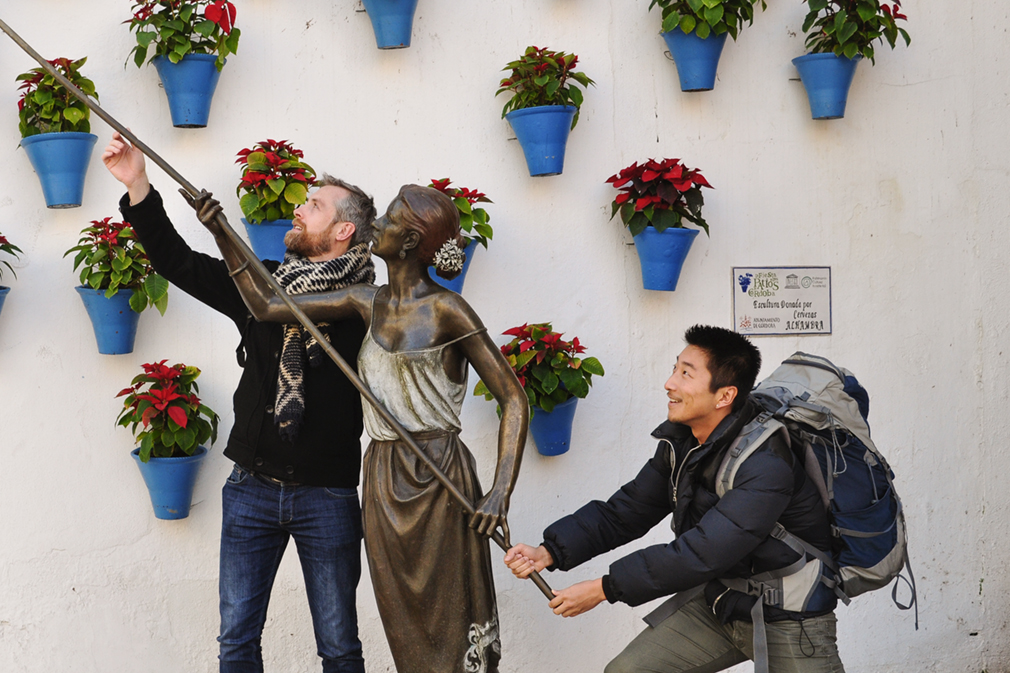 Two men posing with a bronze statue in a public patio