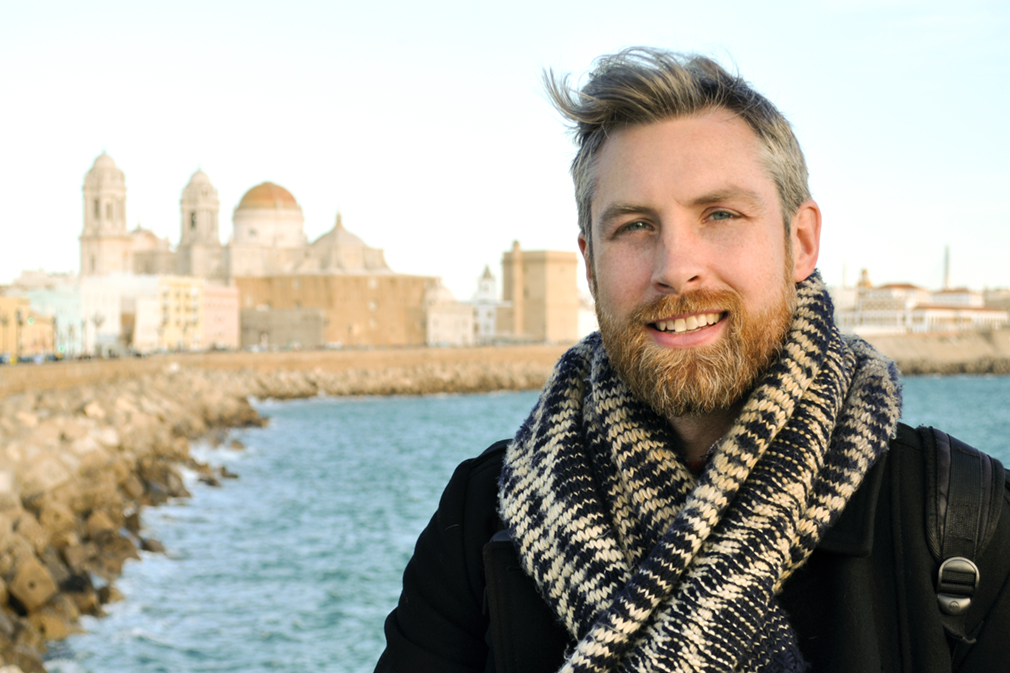 A man poses before an old city waterfront