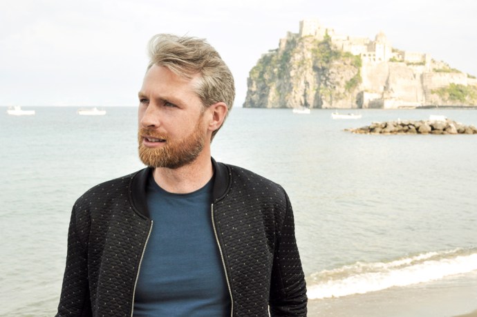 Man on a beach with an island and ancient city in the background