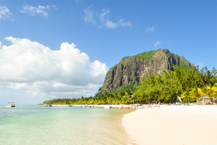 A tropical, sandy beach with transparent waters and a mountain backdrop