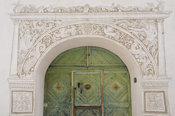 Wooden green door with decoratively etched arch