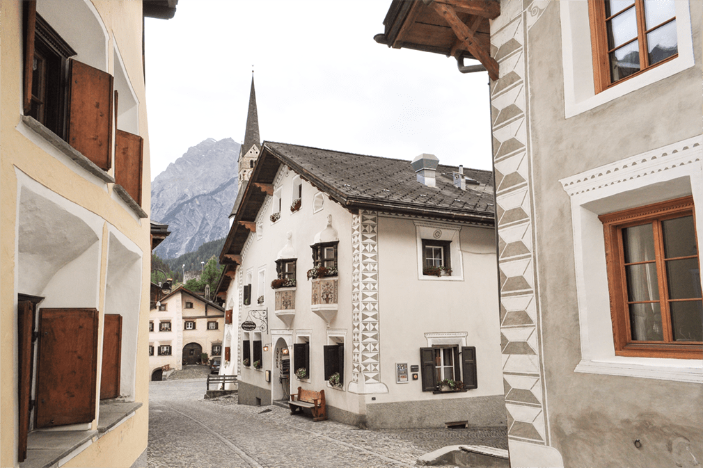 A cobbled village street with traditional buildings featuring ornate wall decorations