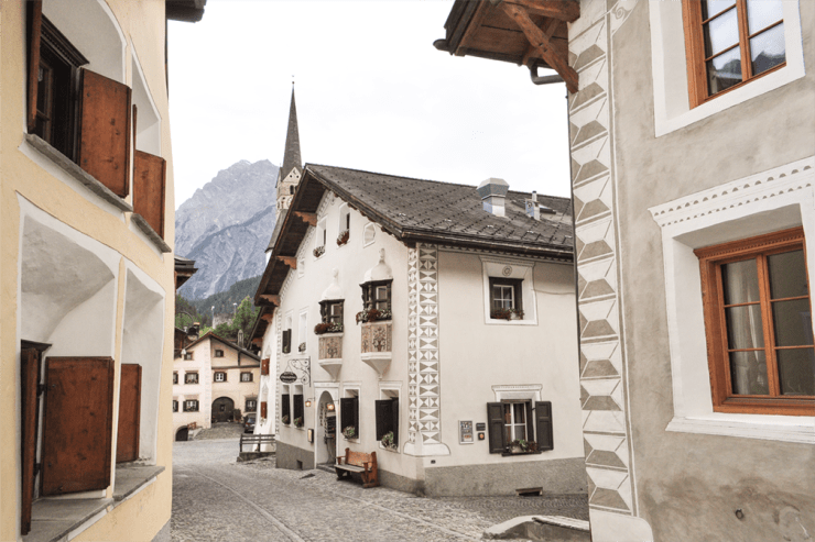 A cobbled village street with traditional buildings featuring ornate wall decorations