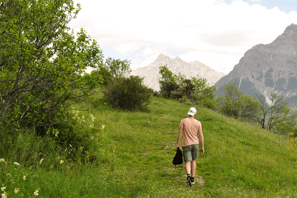 Man in baseball cap walking through a green clearing