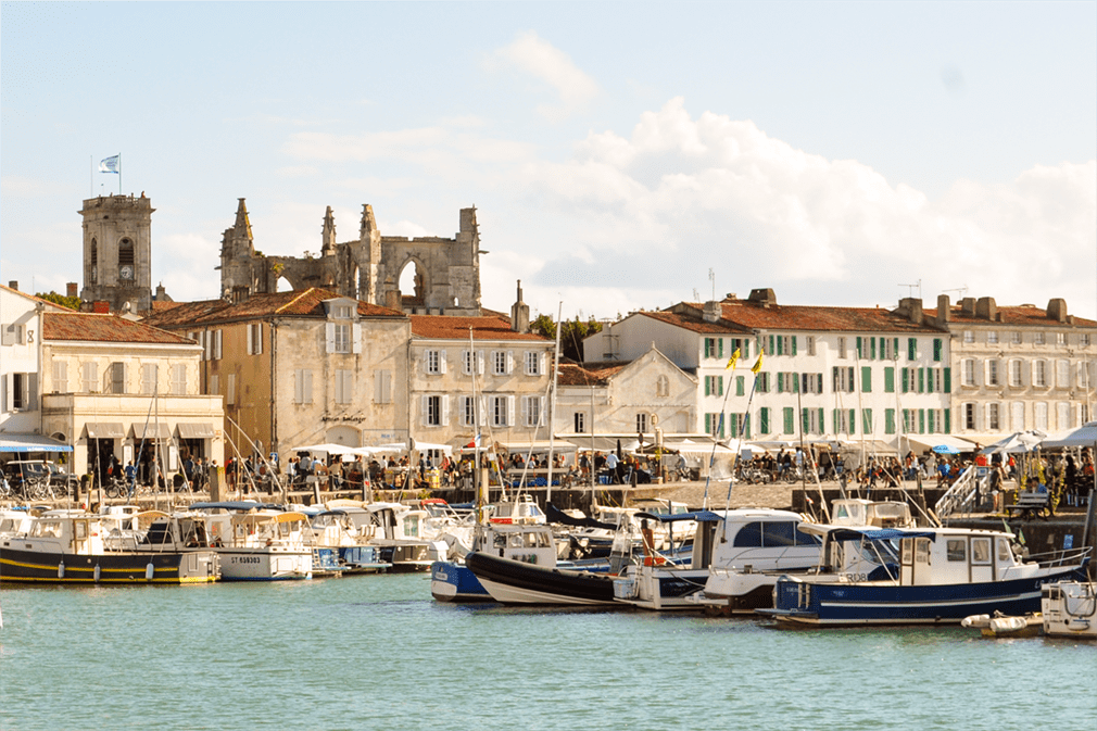 Village waterfront with castle ruins and tower in backdrop