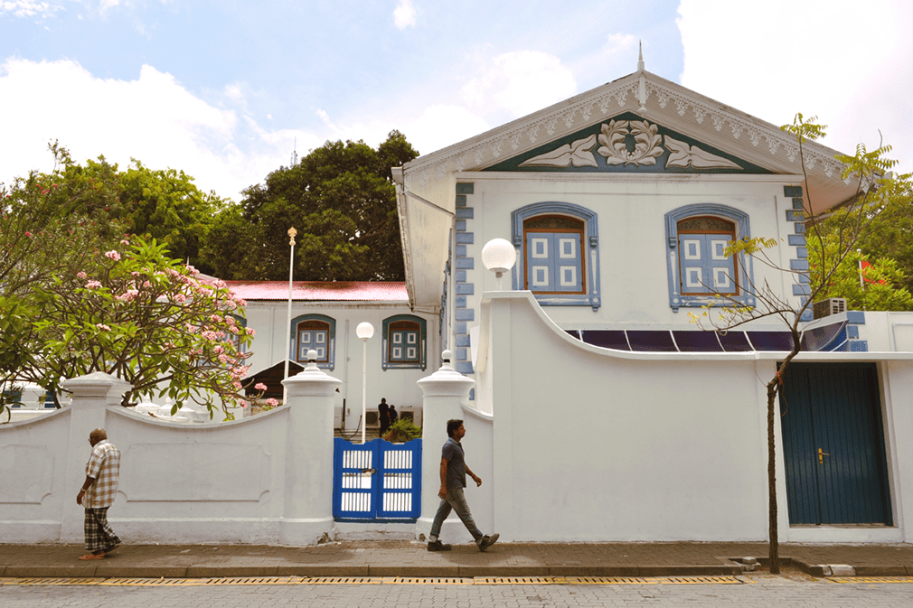 Two men walk in front of colonial-style building