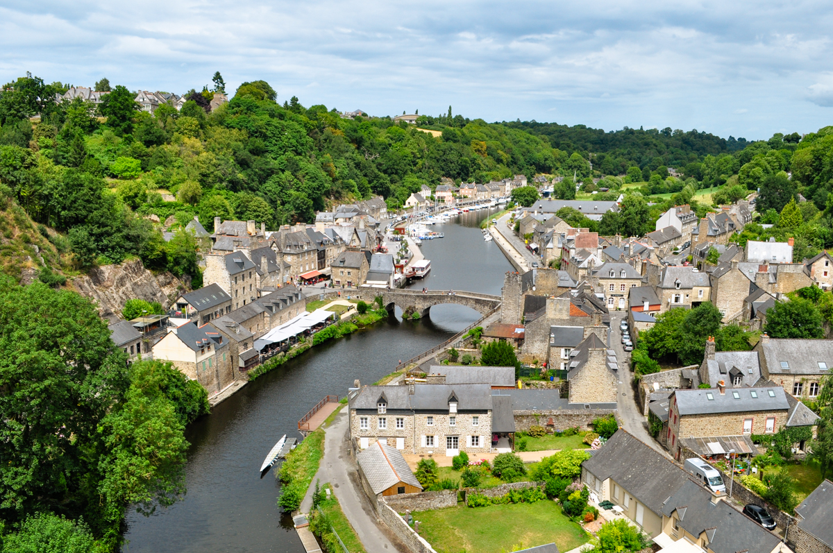 A river runs through a small stone town in a forested valley