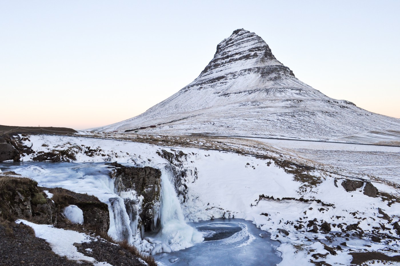 Triangle-shaped mountain behind a frozen waterfall