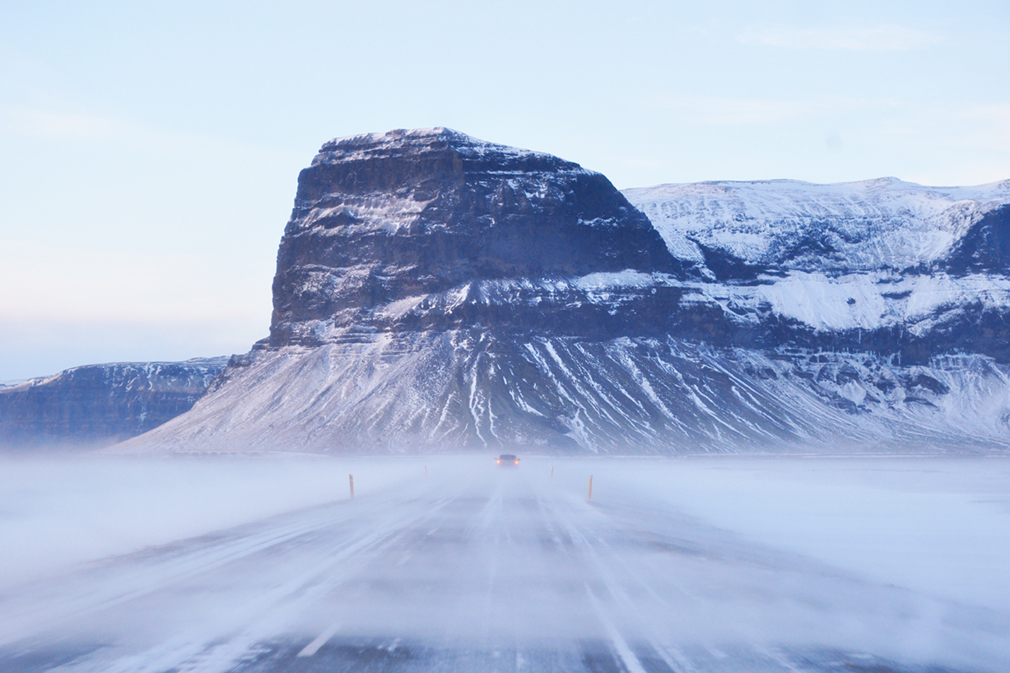 A highway road blanketed by thick drifts of snow