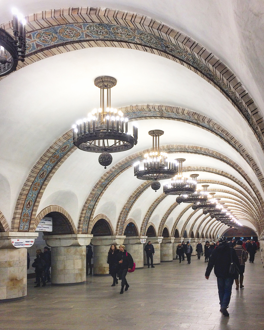 An underground passageway featuring large chandeliers and mosaics