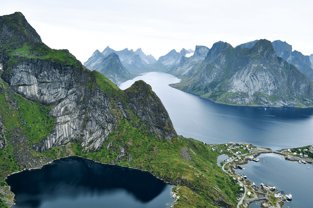 Panoramic view of jagged mountaintops, fjords, and a village archipelago