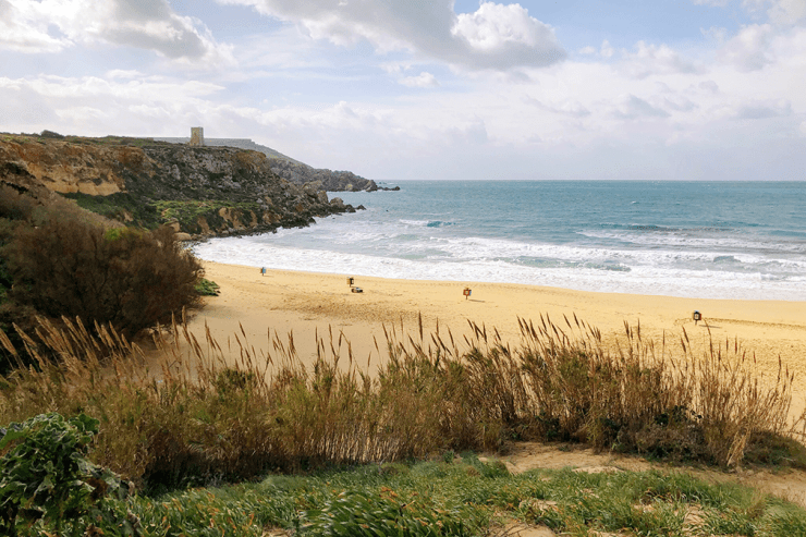 An empty beach with golden sands and watchtower in the distance