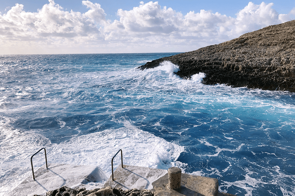Waves crash onto the rocks at Malta's Blue Grotto