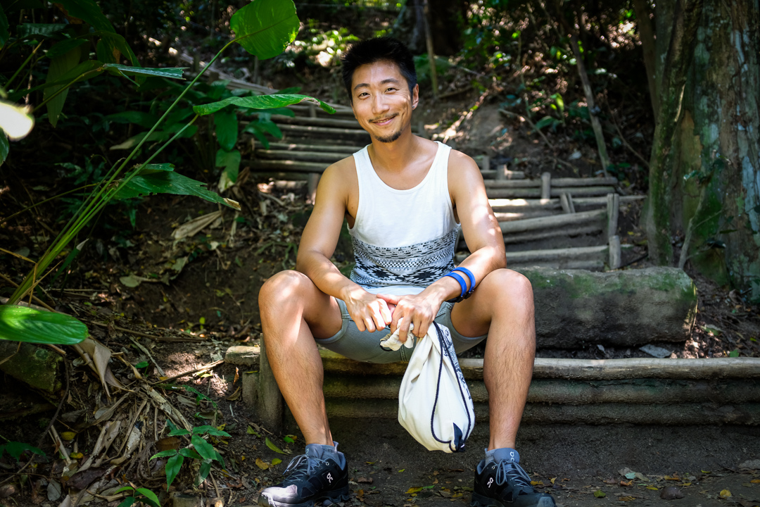 Smiling man sitting in front of jungle pathway
