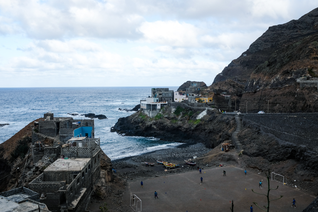 A group of boys playing soccer below a cliffside village
