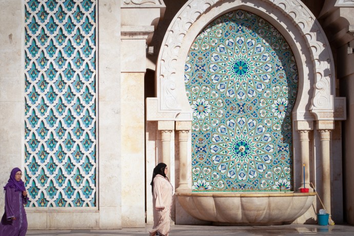 Women in hijab walk in front of zellige tilework