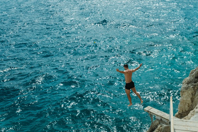 A man diving from a wooden plank into the ocean