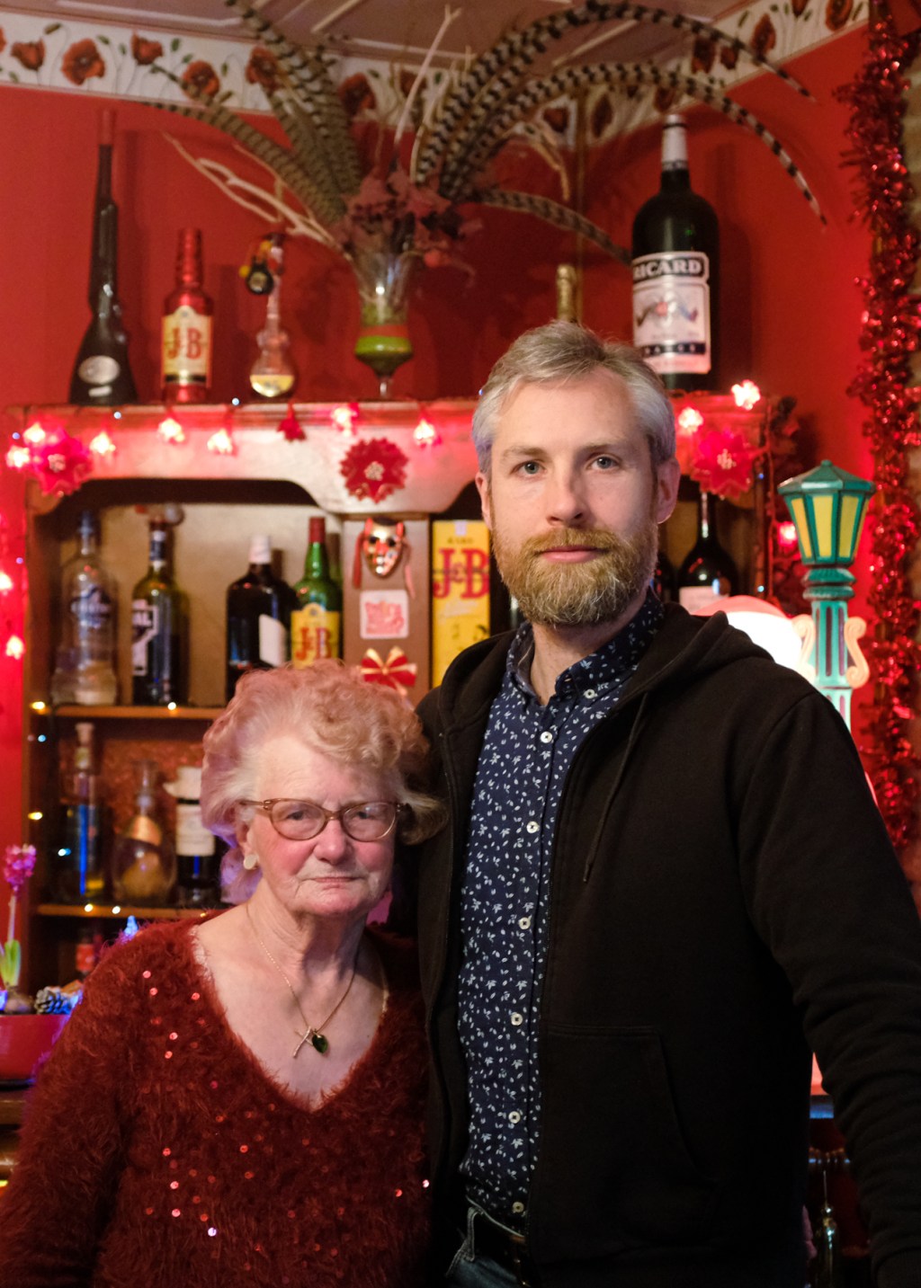 A man and elderly woman post in front of a red living room