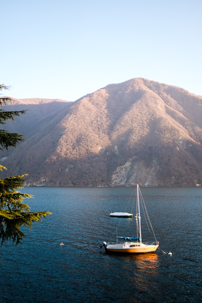 A yellow sailboat out in water at sunset