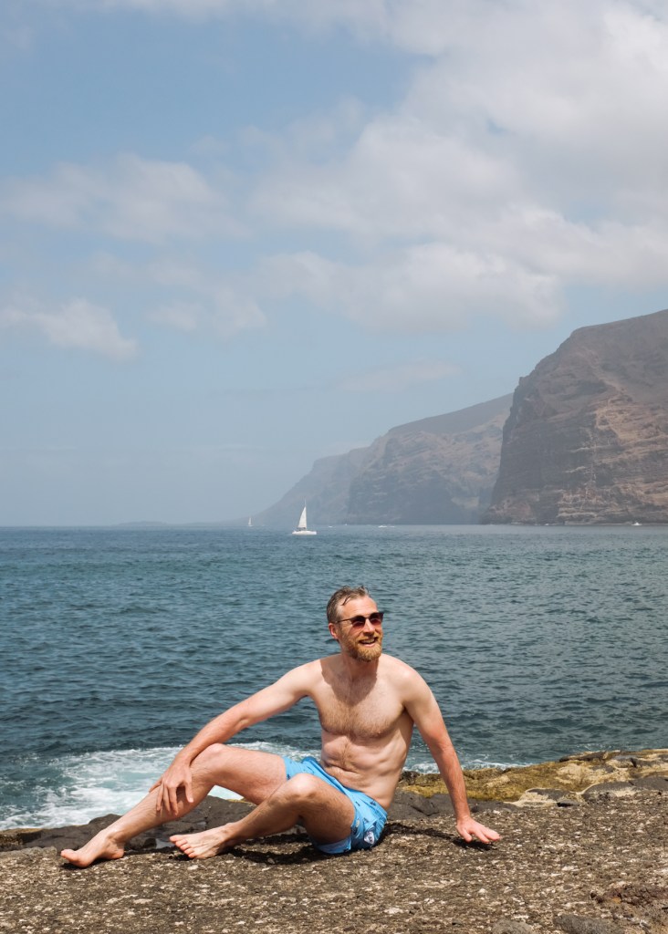 A sunbathing man posing in front of large cliffs