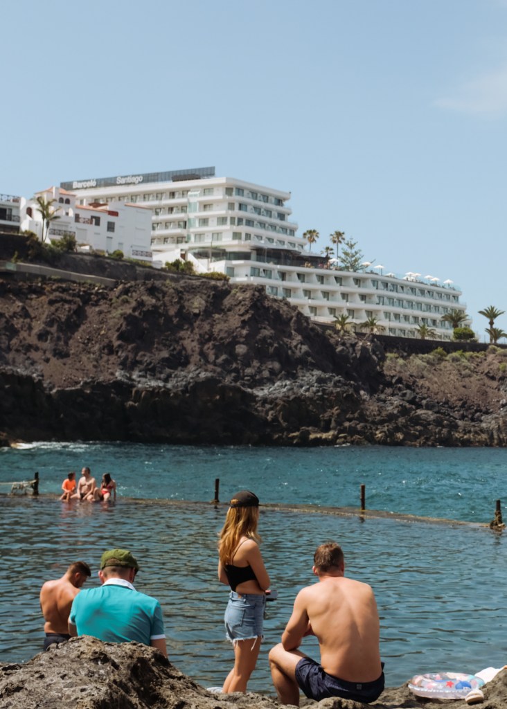 Tourists enjoying a natural rock pool by the sea