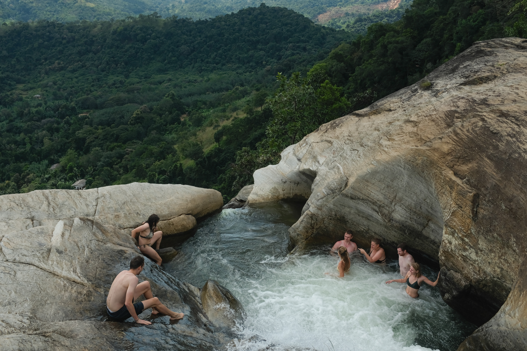 A group of people bathing at the top of a waterfall