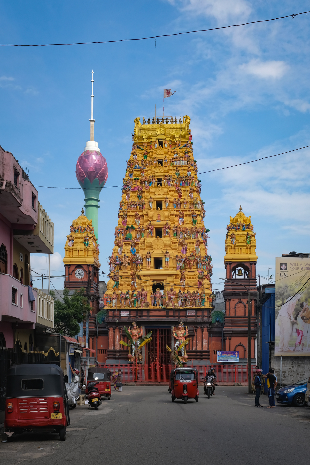 The entrance tower of a Hindu temple and a lotus-shaped skyscraper in the background